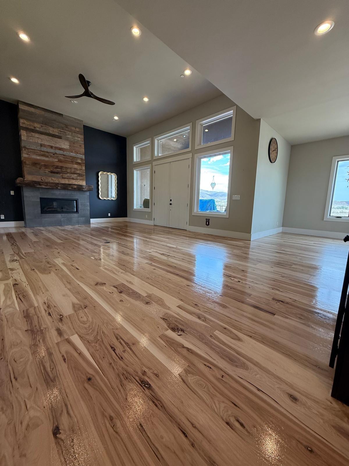 Large living room with newly refinished hardwood floors in a medium tone, modern fireplace and décor