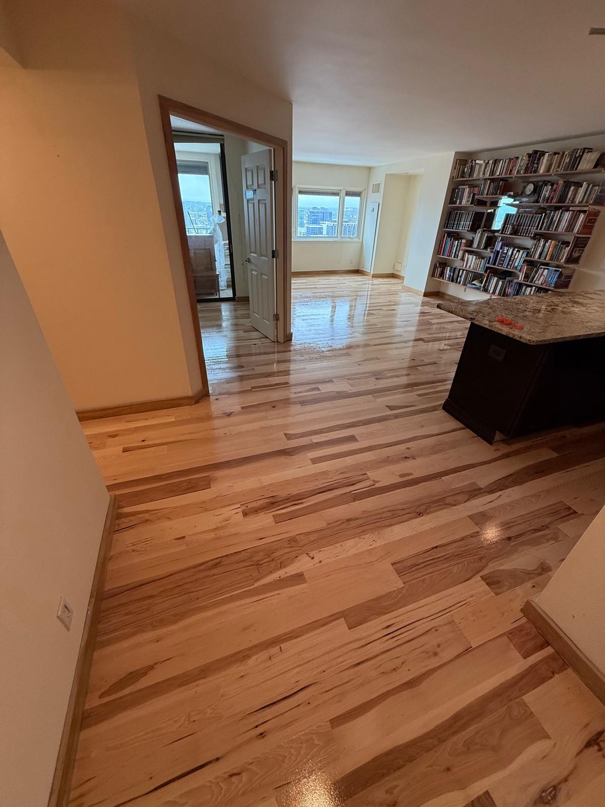 Open loft or apartment space with refinished hardwood flooring in a medium tone, high ceilings and expansive layout