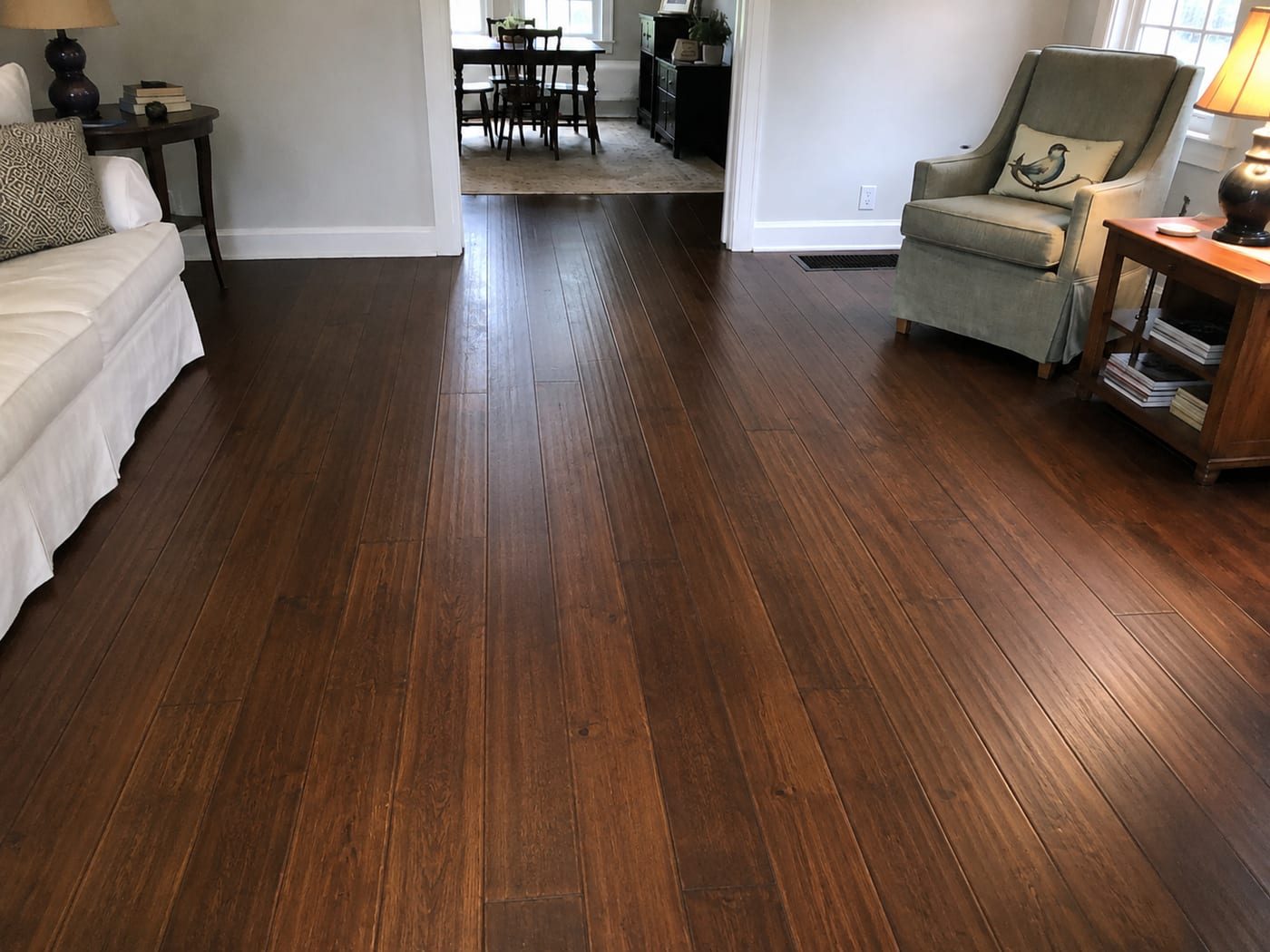 The same wide-plank floor after restoration, refinished to a rich, deep walnut tone