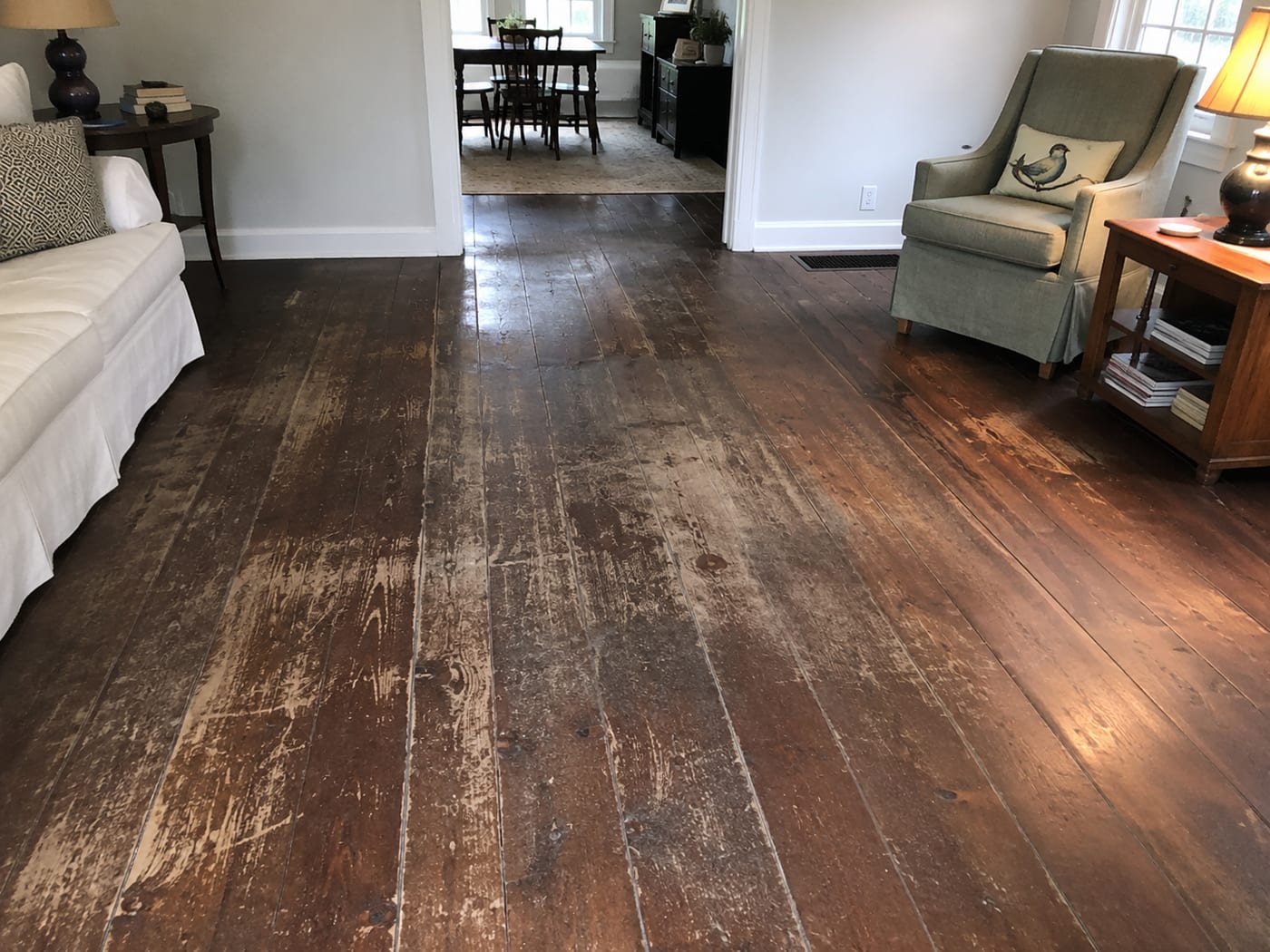 Wide-plank hardwood floor worn and stripped of its finish before restoration